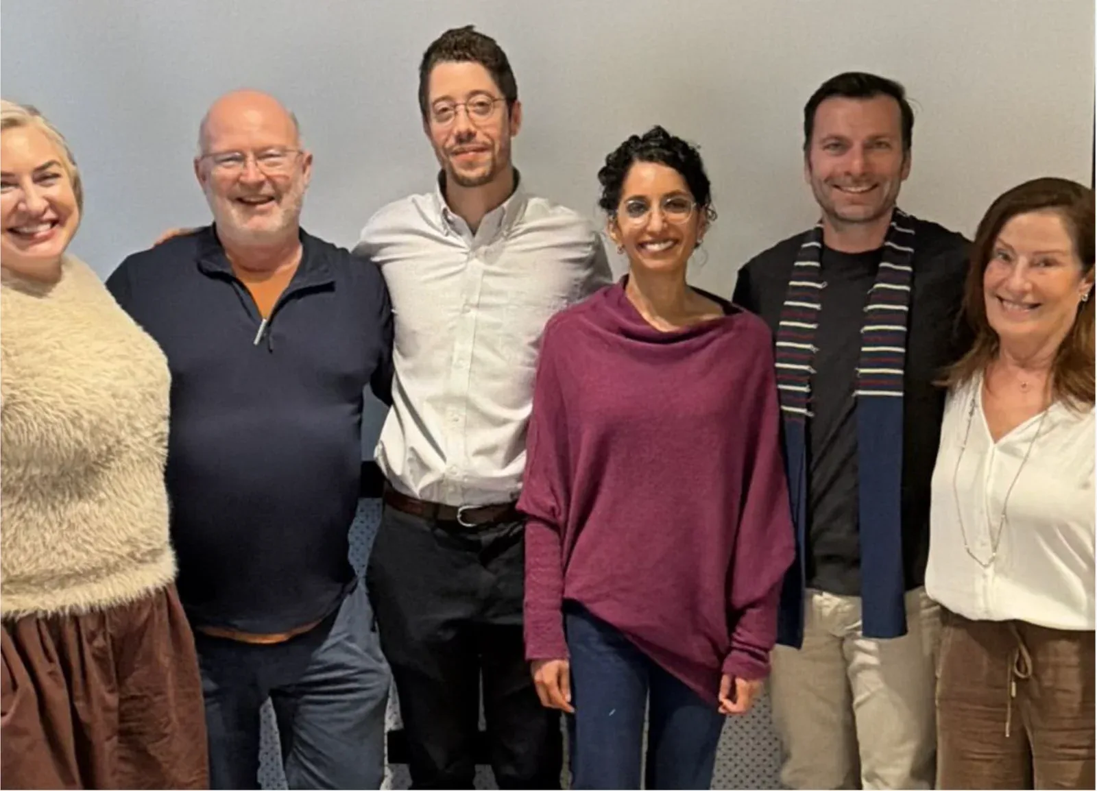 Six participants of the Brisbane workshop, including Dr. Nicolas Garel, standing side by side in front of a light wall.